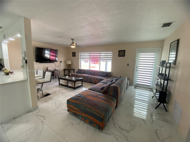 living area with visible vents, marble finish floor, a textured ceiling, and a ceiling fan