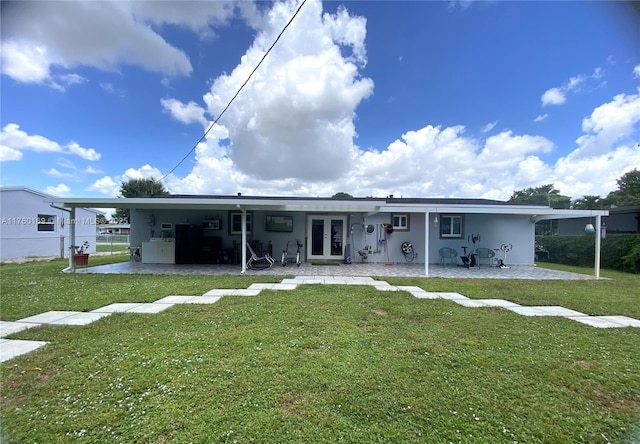 rear view of house with stucco siding, french doors, a yard, and fence