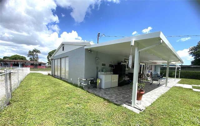 view of side of property featuring fence, a yard, a patio area, and independent washer and dryer