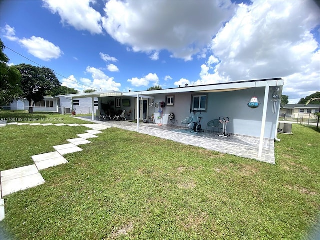 rear view of house featuring an attached carport, a patio, a lawn, and stucco siding