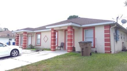 view of front facade featuring concrete driveway and a front yard