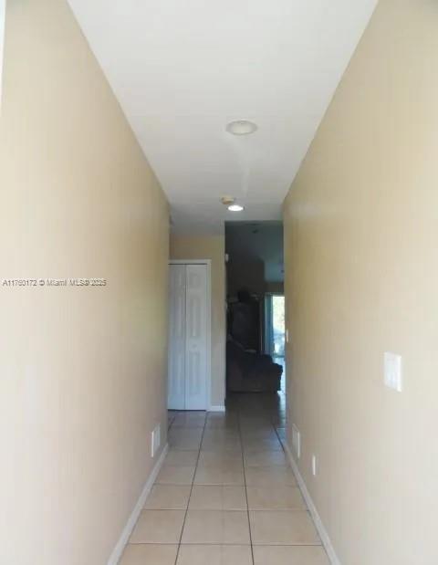 hallway with light tile patterned floors and baseboards