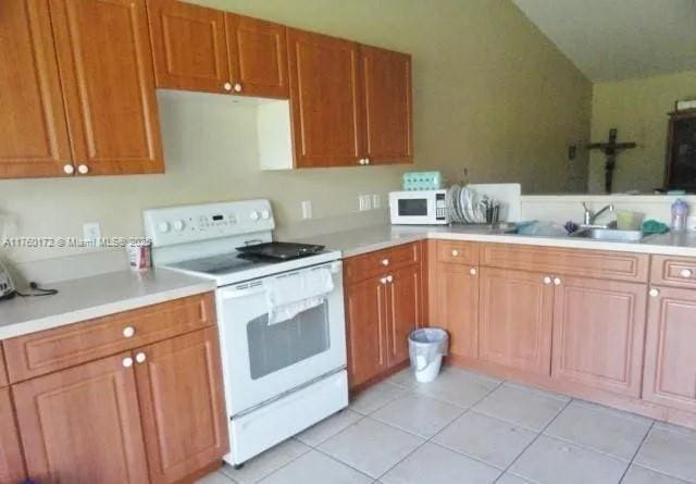 kitchen featuring white appliances, light countertops, and a sink