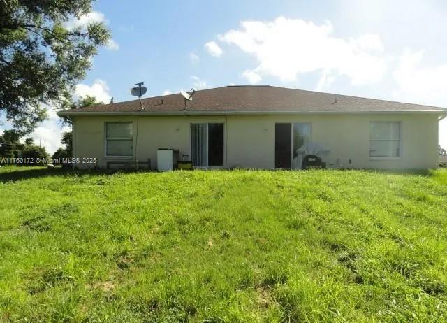 back of house with a yard and stucco siding