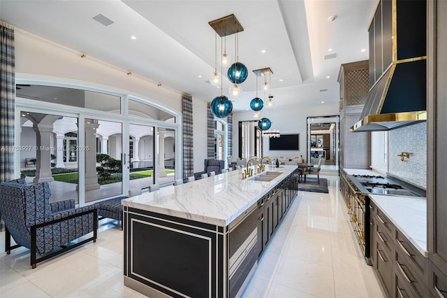 kitchen with a raised ceiling, exhaust hood, light tile patterned floors, and a sink