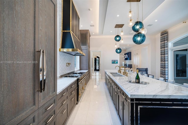 kitchen with light stone countertops, a sink, stainless steel range, a large island, and tasteful backsplash