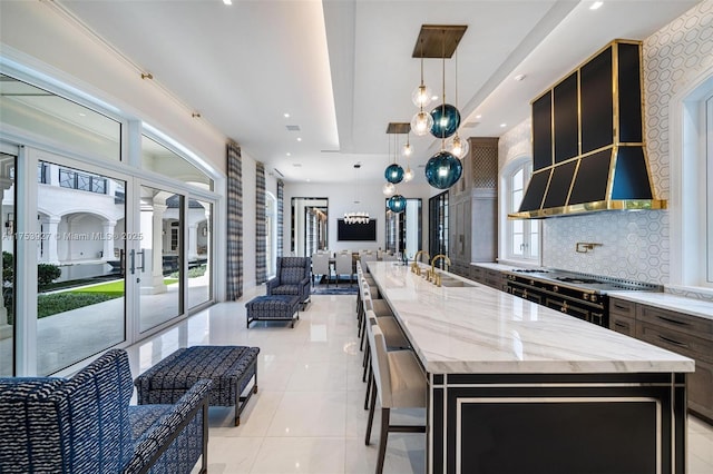 kitchen with a spacious island, open floor plan, decorative backsplash, light tile patterned flooring, and a sink