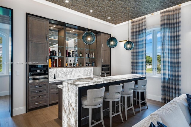 bar with wet bar, dark wood-style floors, baseboards, and an ornate ceiling