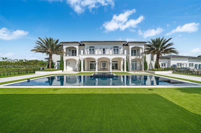 back of house featuring a lawn, stucco siding, a balcony, a patio area, and an outdoor pool