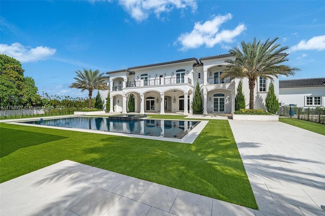 back of house with a balcony, a yard, and fence