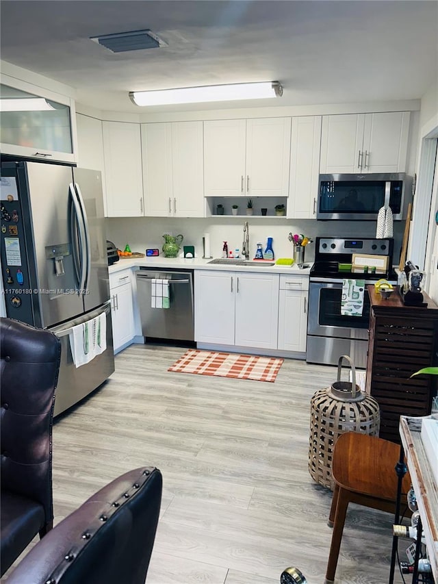 kitchen with a sink, white cabinets, visible vents, and stainless steel appliances