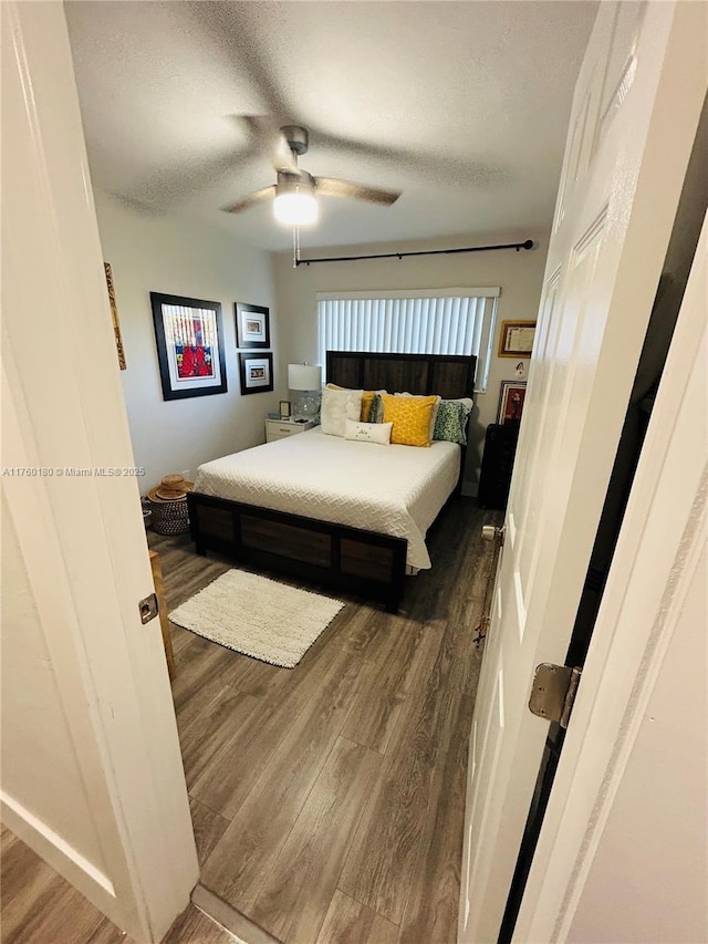 bedroom with dark wood finished floors, a textured ceiling, and ceiling fan