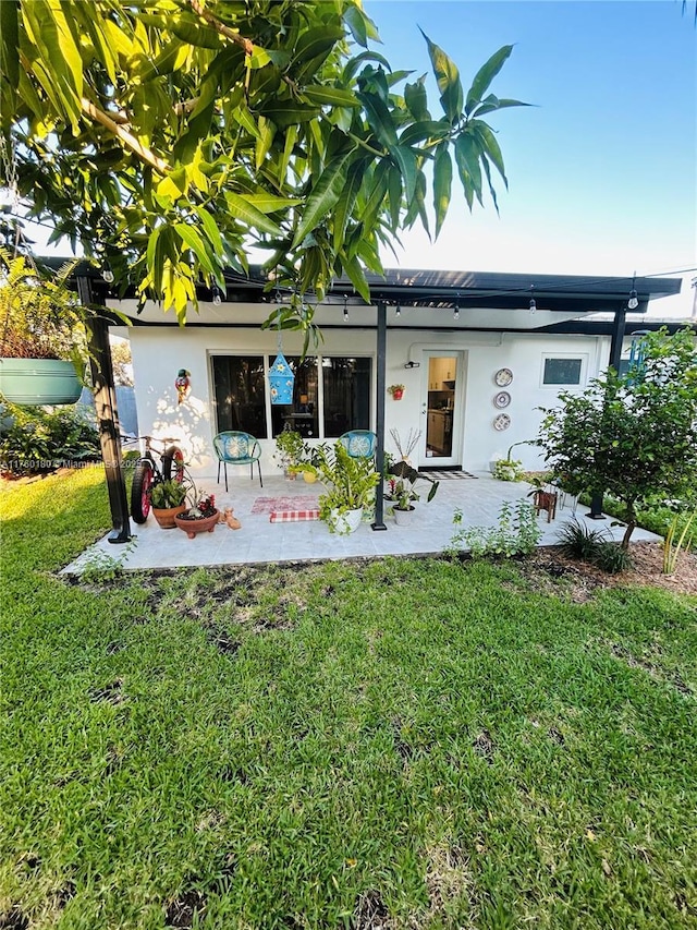 back of property featuring a yard, a patio, and stucco siding