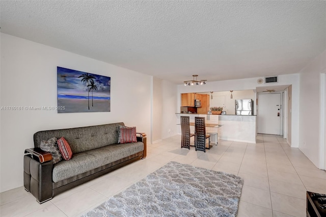 living area with light tile patterned floors, visible vents, and a textured ceiling