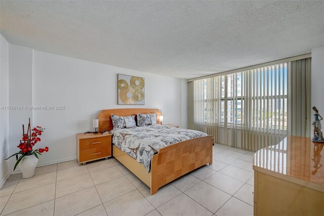 bedroom with light tile patterned floors, a textured ceiling, and baseboards