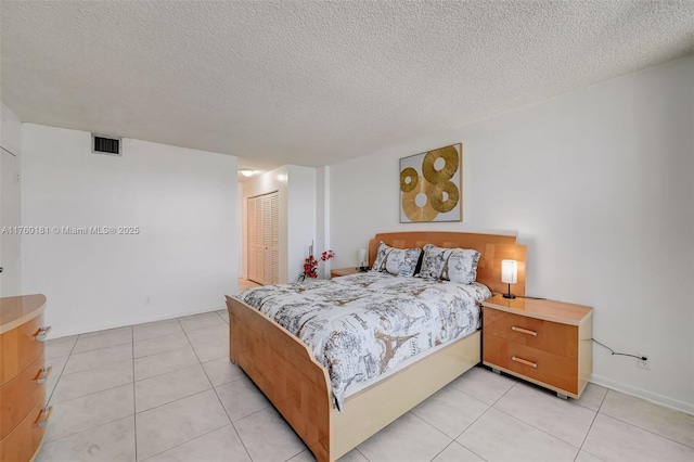 bedroom featuring visible vents, a textured ceiling, a closet, and light tile patterned flooring