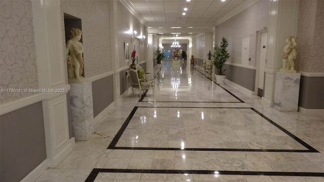 corridor featuring a decorative wall, a wainscoted wall, and marble finish floor