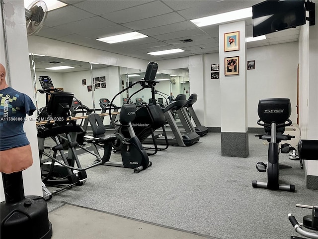 workout area featuring visible vents, a paneled ceiling, and baseboards