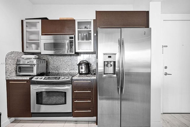 950 Brickell Bay Dr Unit 3605, Miami, FL 33131 - kitchen with dark brown cabinets, glass insert cabinets, tasteful backsplash, and stainless steel appliances