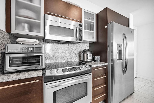 950 Brickell Bay Dr Unit 3605, Miami, FL 33131 - kitchen with dark brown cabinetry, decorative backsplash, stainless steel appliances, and glass insert cabinets