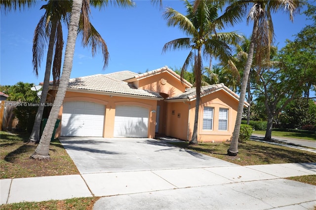 mediterranean / spanish-style home featuring stucco siding, an attached garage, a tile roof, and driveway