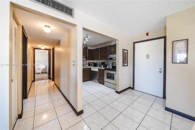 kitchen with visible vents, dark brown cabinetry, appliances with stainless steel finishes, exhaust hood, and light countertops