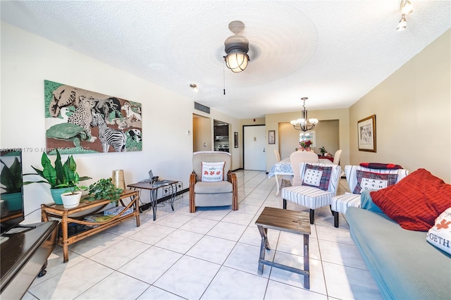 living area with light tile patterned floors, a notable chandelier, and a textured ceiling