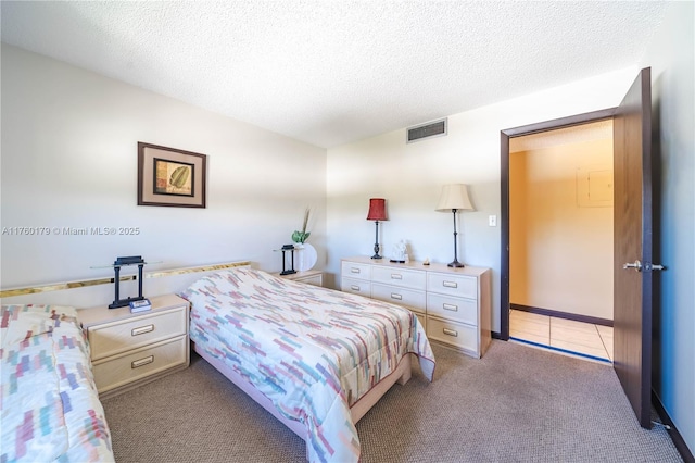 bedroom with light tile patterned floors, visible vents, light carpet, and a textured ceiling