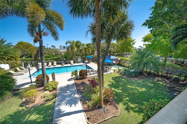 community pool featuring a patio area, fence, and a lawn