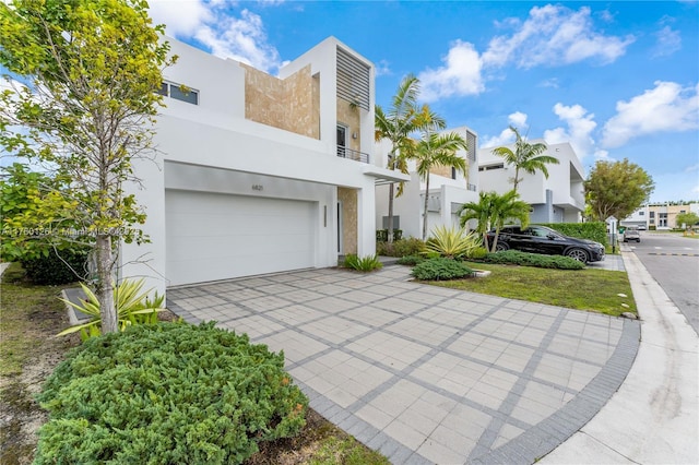 view of front of home with decorative driveway, a garage, a residential view, and stucco siding