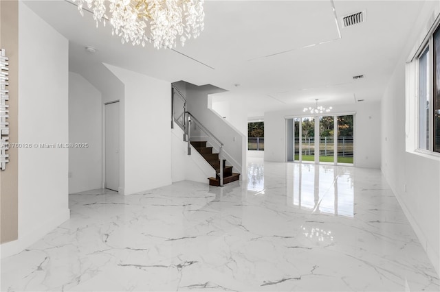 empty room featuring visible vents, marble finish floor, a chandelier, and stairway