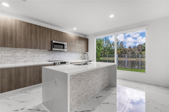 kitchen with a sink, marble finish floor, stainless steel appliances, and modern cabinets