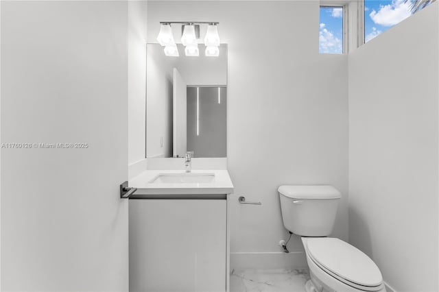 half bath with baseboards, toilet, marble finish floor, and vanity