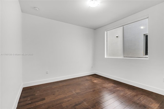 unfurnished room featuring dark wood-type flooring and baseboards