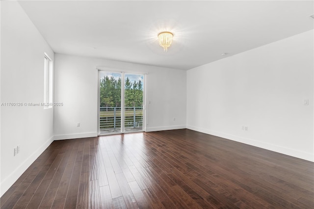 unfurnished room with baseboards and dark wood-style flooring