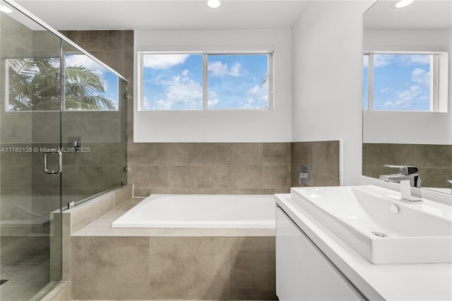 bathroom with plenty of natural light, a stall shower, vanity, and a garden tub