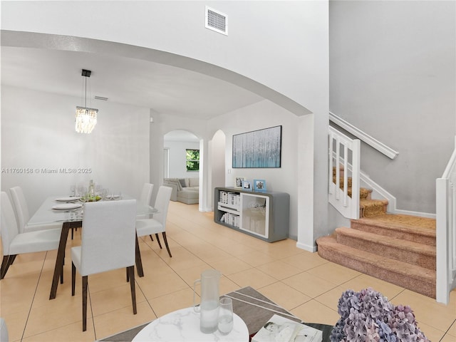 dining room featuring stairway, visible vents, an inviting chandelier, arched walkways, and tile patterned flooring