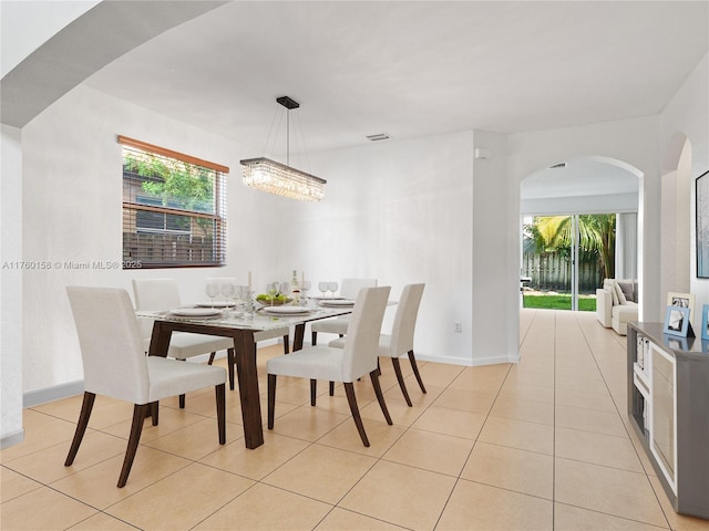 dining room with visible vents, baseboards, arched walkways, light tile patterned flooring, and a notable chandelier