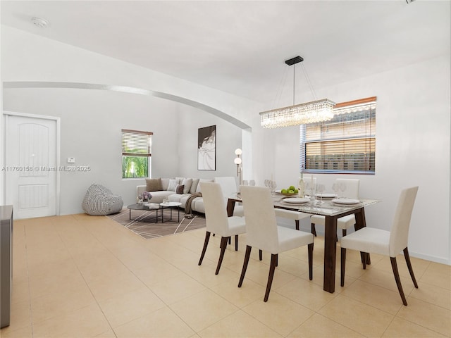 dining room with an inviting chandelier, light tile patterned floors, and arched walkways