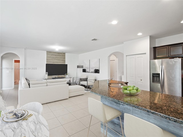 living area featuring visible vents, light tile patterned floors, recessed lighting, and arched walkways