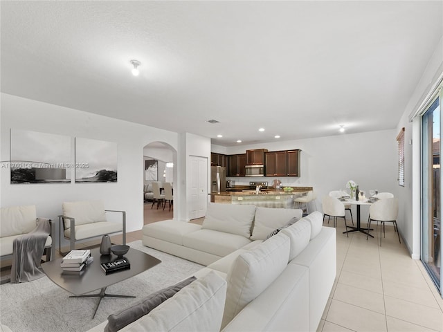 living room featuring recessed lighting, visible vents, arched walkways, and light tile patterned flooring