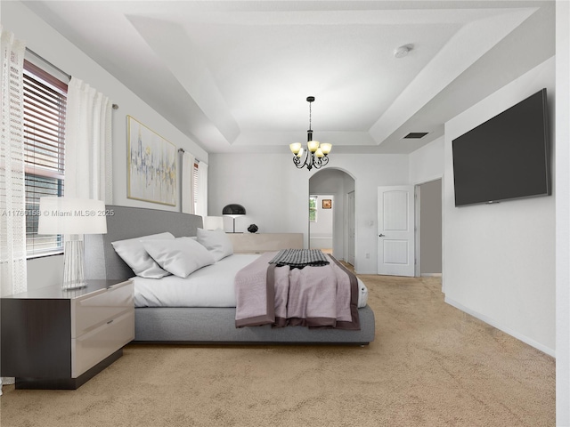 bedroom with light carpet, a raised ceiling, arched walkways, baseboards, and a chandelier