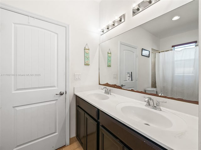 full bath with a sink, toilet, and double vanity