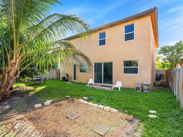 rear view of property featuring a yard, a fenced backyard, and stucco siding