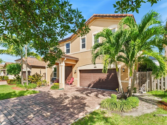 mediterranean / spanish house featuring stucco siding, decorative driveway, an attached garage, and a tiled roof