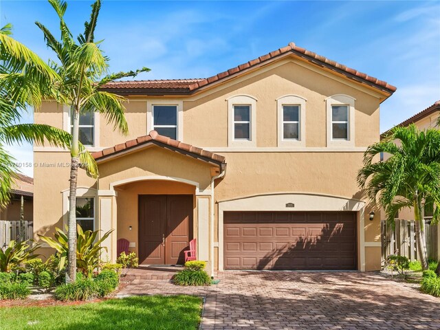 mediterranean / spanish home with stucco siding, driveway, a tile roof, and a garage