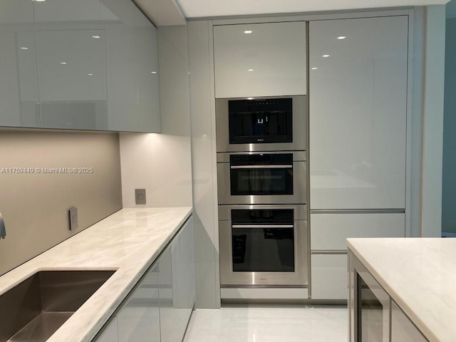 kitchen with a sink, double oven, modern cabinets, and white cabinets