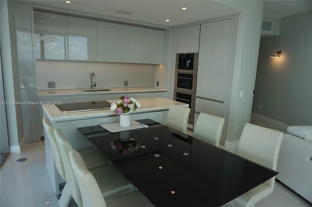 kitchen featuring visible vents, modern cabinets, a sink, a center island, and black electric cooktop