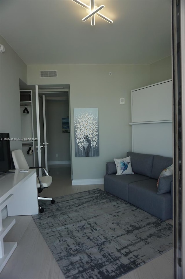 living area featuring visible vents, baseboards, and wood finished floors