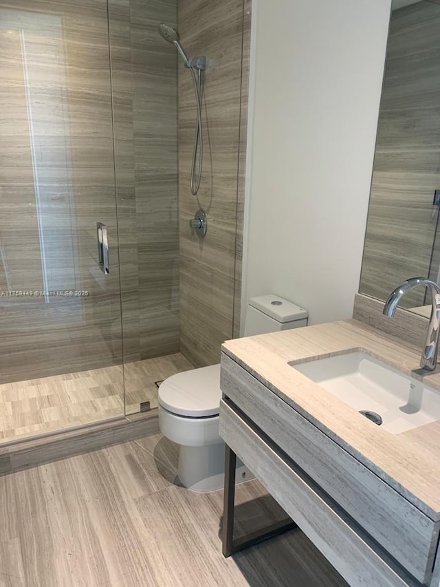 full bath with toilet, a stall shower, and vanity